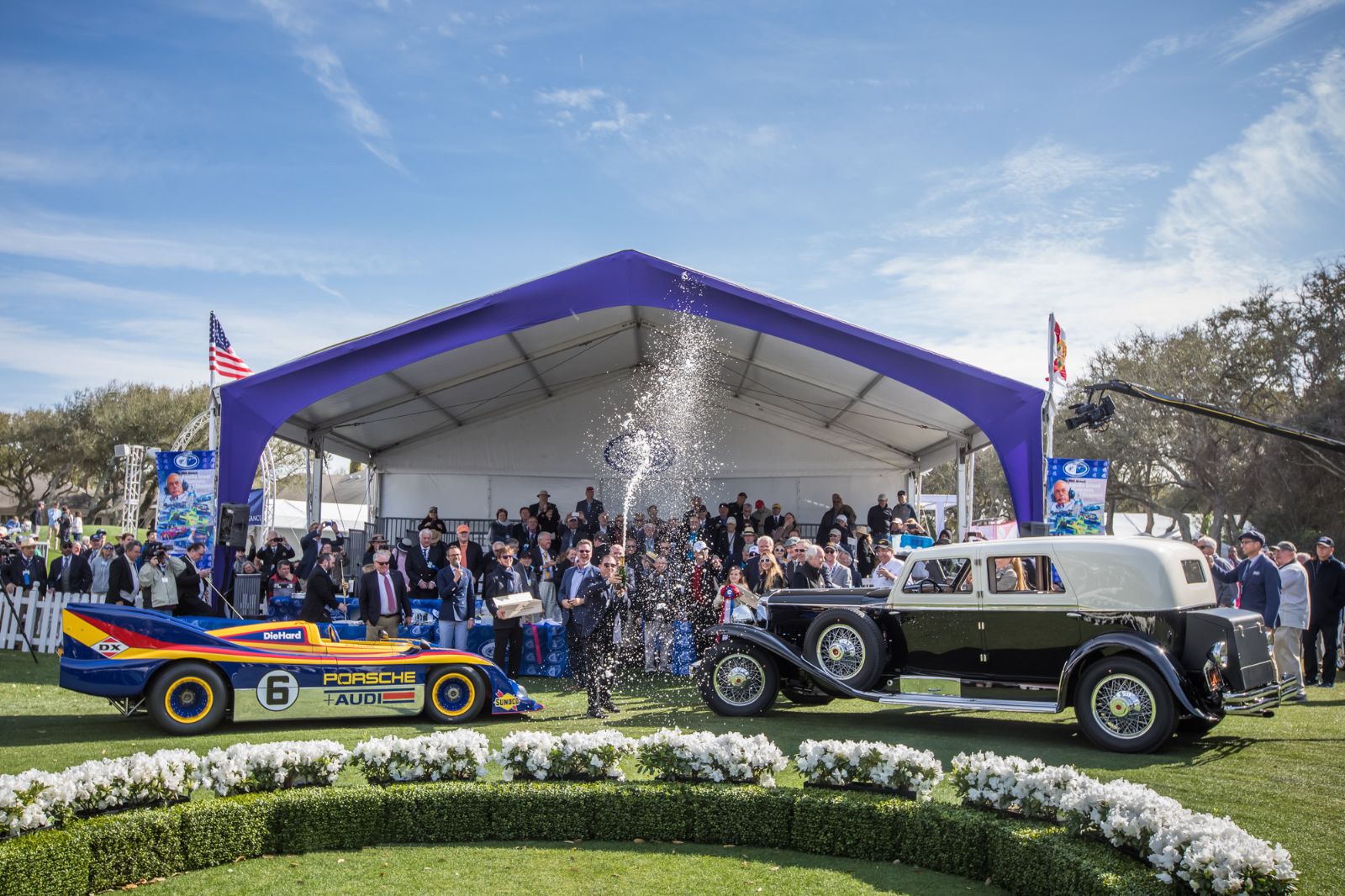 Champagne sprayed between a Can-Am Porsche and a Duesenberg town car at the Best in Show presentation at the Amelia Island Concours d’Elegance