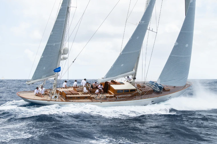 A classic yacht heeling under full sail through the swell, her crew on the teak deck, at the Antigua Classic Yacht Regatta, a mid-April engagement in the season calendar of The Mansa Court