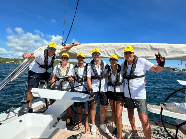 A crew in matching yellow caps and lifejackets gathered at the helm of their yacht at Antigua Sailing Week, a late-April engagement in the season calendar of The Mansa Court