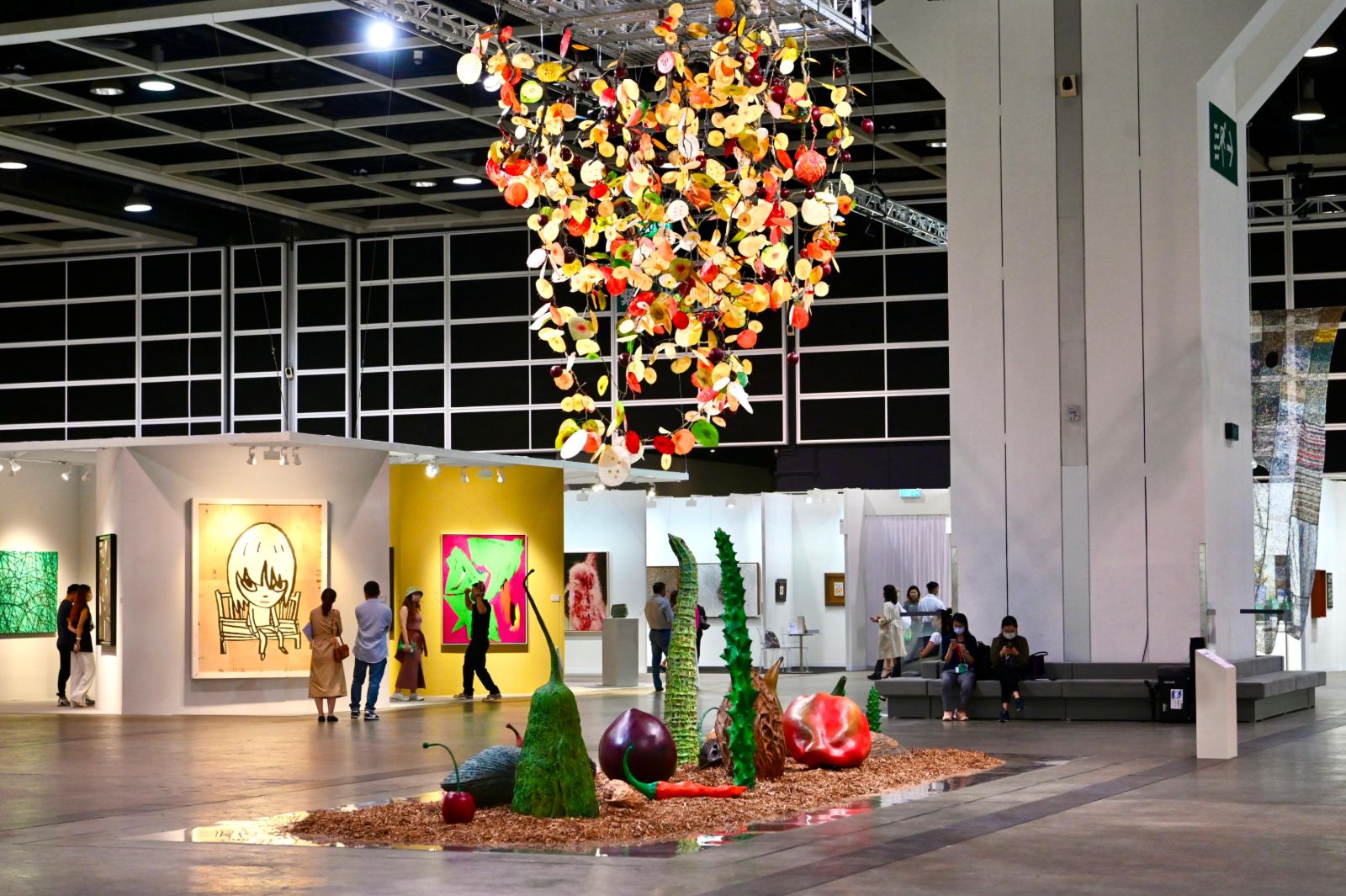A suspended fruit installation hanging above the Encounters sector at Art Basel Hong Kong, attended by members of The Mansa Court