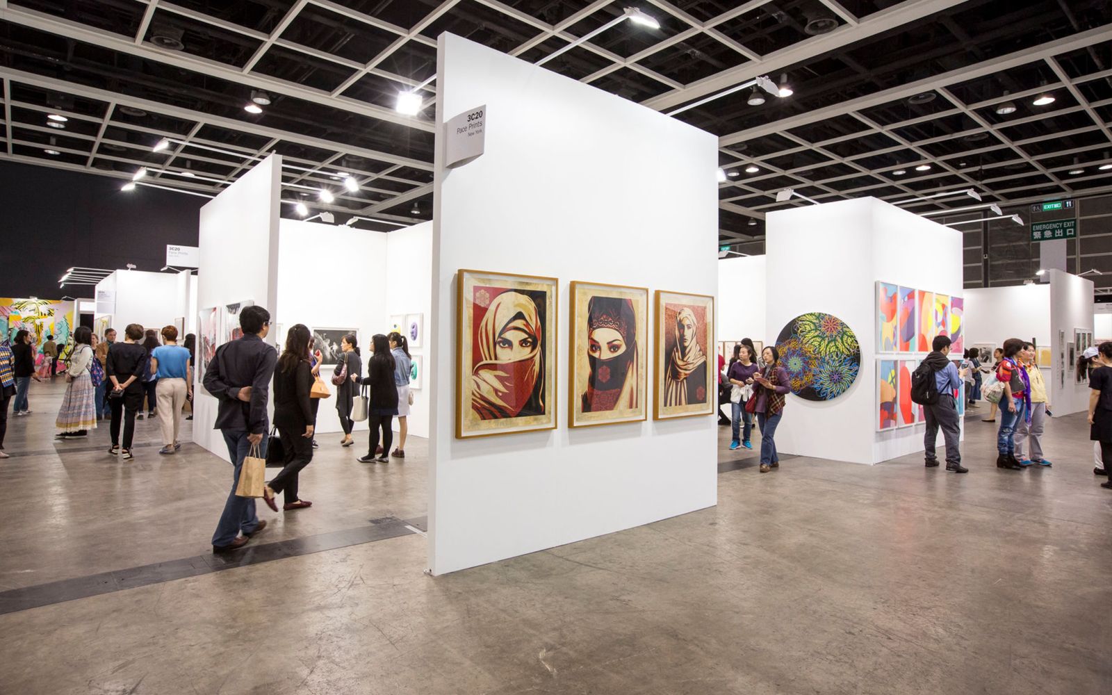 Visitors between white gallery stands hung with framed prints at Art Basel Hong Kong, the March fair at the Convention and Exhibition Centre The Mansa Court keeps in its calendar