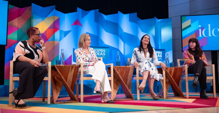 Four panellists seated on the stage above a striped carpet, the festival set rising behind them, at the Aspen Ideas Festival, a late-June engagement in the season calendar of The Mansa Court