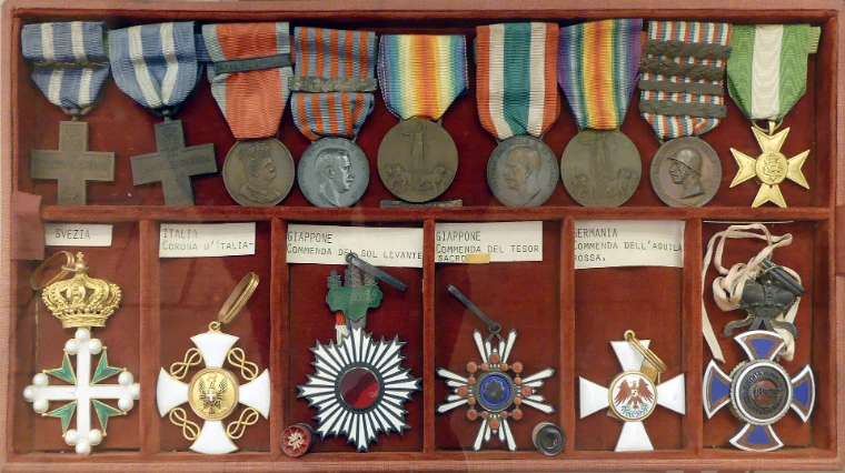 A case of orders and medals on red velvet, among them a white and green enamelled cross beneath a crown (2023).