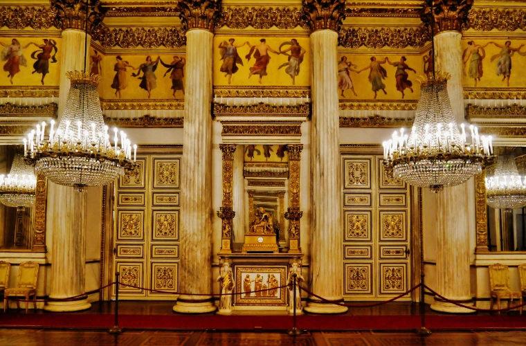 White marble columns, gilded panels and a frieze of painted dancers along a wall of the Royal Palace of Turin’s ballroom (2020).