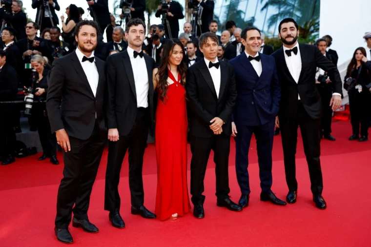 A party in black tie and a red gown on the red carpet before a gala screening. The Cannes Film Festival at the Palais des Festivals, in the season calendar of The Mansa Court