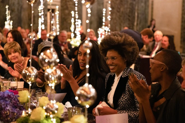 Guests applaud at a long table hung with strings of light and glass globes. A gala dinner, shown for Carnegie Hall Opening Night Gala in the season calendar of The Mansa Court