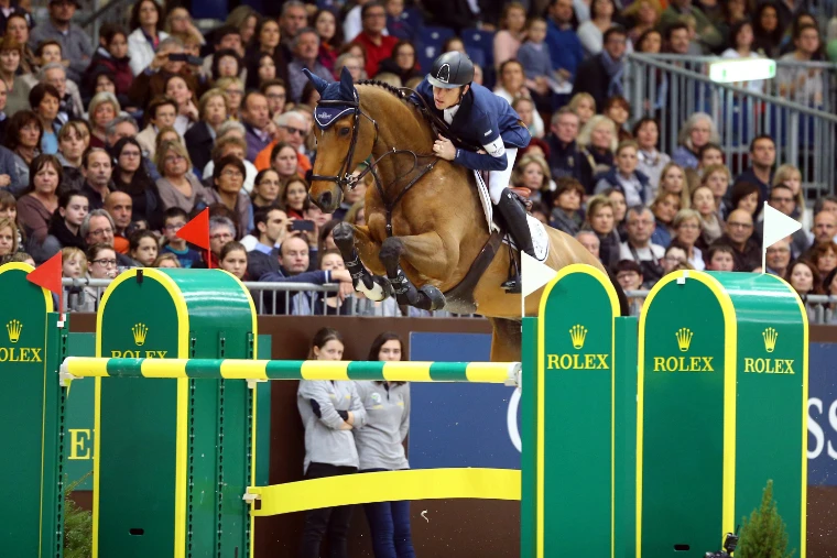 Scott Brash and Hello Sanctos clear a green Rolex fence in the Rolex Grand Prix, a packed stand of spectators behind (2014).