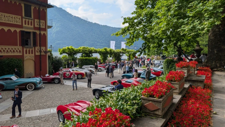 Classic cars and guests fill the gravel before the red villa, beds of begonias in the foreground and the lake beyond the wisteria. The Concorso d’Eleganza Villa d’Este on Lake Como, in the season calendar of The Mansa Court