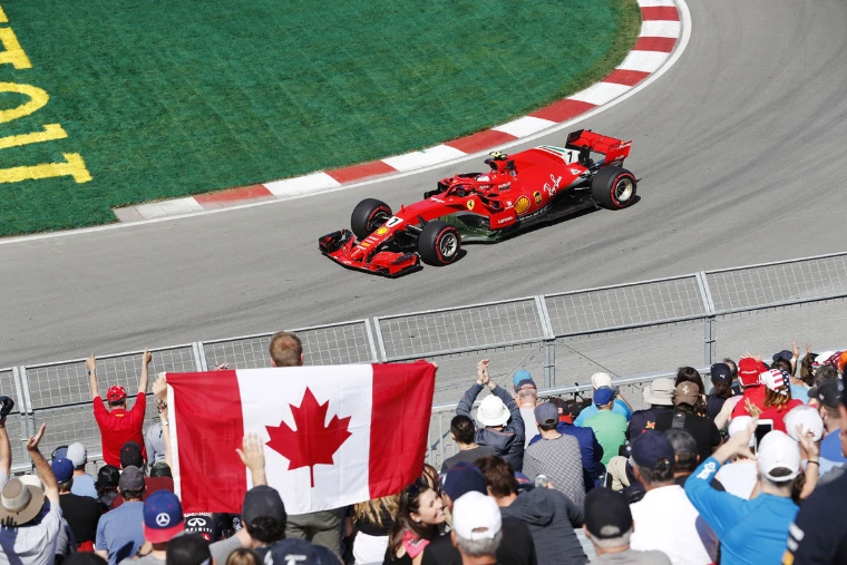 A Canadian flag held up in the crowd as a car passes the fence. The Formula 1 Canadian Grand Prix at the Circuit Gilles Villeneuve, Montreal, in the season calendar of The Mansa Court