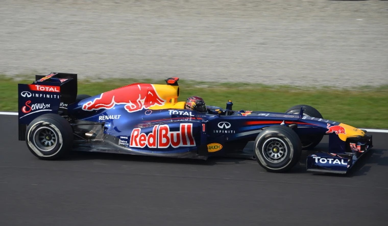 A dark blue Red Bull Formula One car at speed on the circuit (2011).