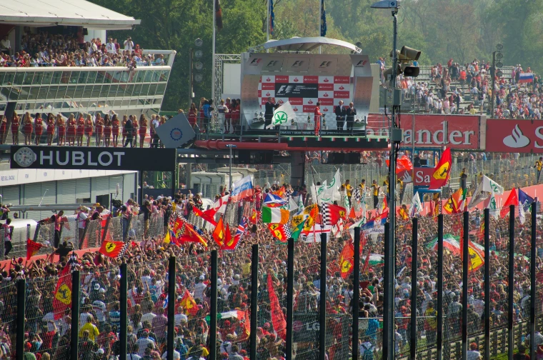 Spectators carrying national and Ferrari flags fill the main straight at Monza beneath the podium after the Italian Grand Prix (2012).