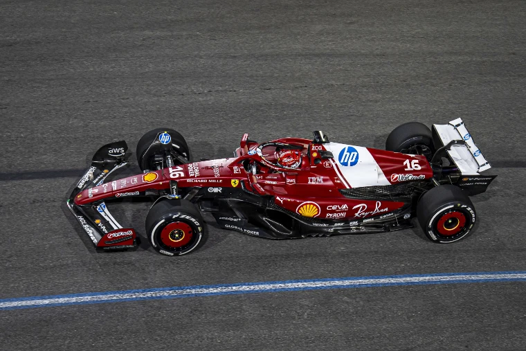 A red and white Ferrari Formula One car numbered 16 on the floodlit track at night, seen from above (2025).