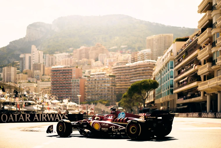 A car sweeps past the harbour front under the towers of Monte Carlo and the Tête de Chien. The Formula 1 Monaco Grand Prix on the streets of Monte Carlo, in the season calendar of The Mansa Court