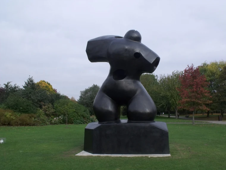 A large black bronze sculpture stands on a plinth on the lawn of the Frieze sculpture park, with autumn-coloured trees behind (2009).