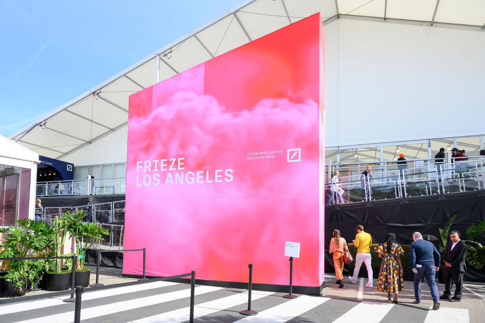 Visitors arriving past the pink entrance wall of the fair tent at Frieze Los Angeles