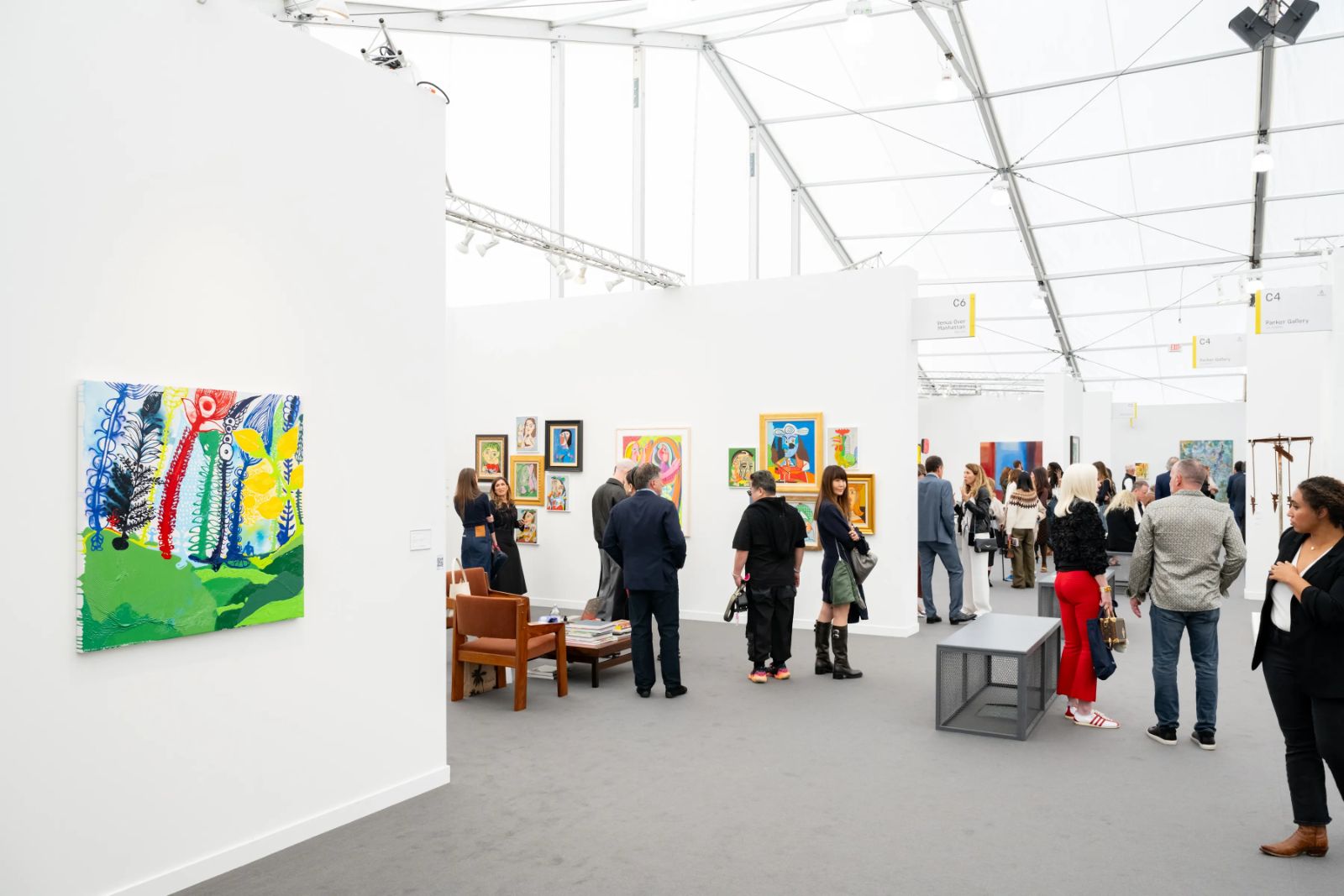 Paintings hung along the white walls of a gallery aisle under the daylit tent at Frieze Los Angeles