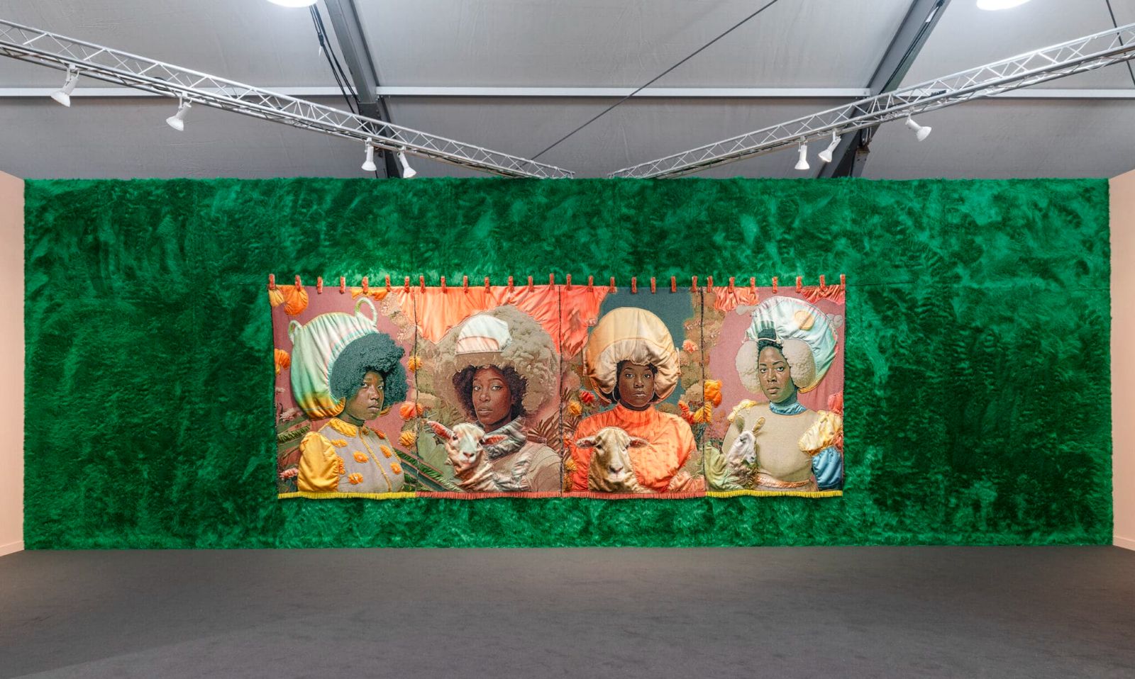 A four-panel textile work hung on a green fur wall in a gallery booth at Frieze Los Angeles