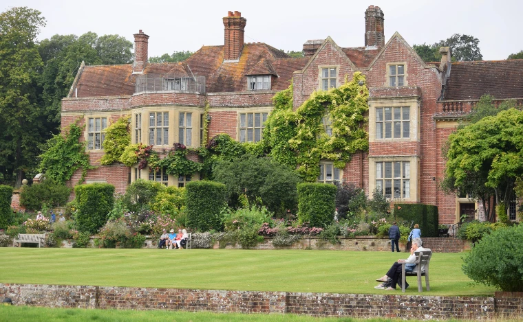 The red-brick Elizabethan house above its lawn, borders and yew hedges. Glyndebourne Festival Opera, near Lewes in East Sussex, in the season calendar of The Mansa Court