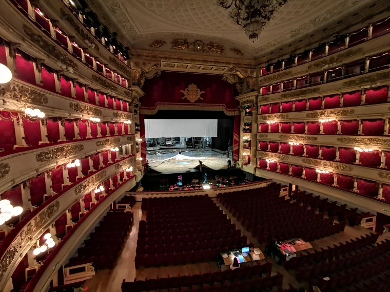 The red and gold horseshoe auditorium of La Scala seen from a box, its tiers of lit boxes curving round the empty stalls towards the stage (2019).