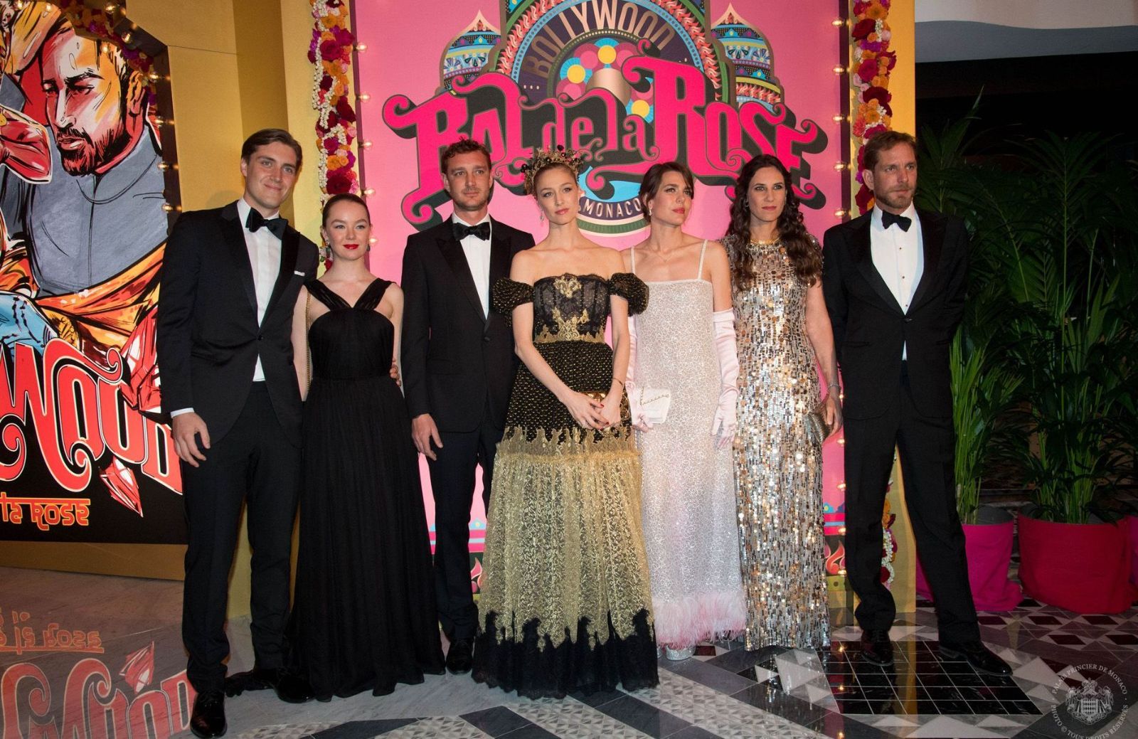 Guests in black tie and evening gowns photographed before the themed Bal de la Rose backdrop at Monte Carlo, an engagement by invitation in The Mansa Court season