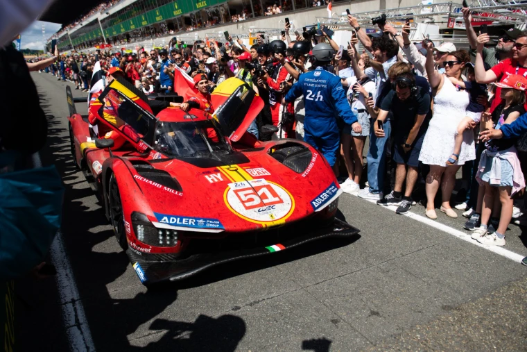 The winning red Ferrari hypercar met by a cheering crowd in the pit lane after the Le Mans 24 Hours, an engagement in the season calendar of The Mansa Court