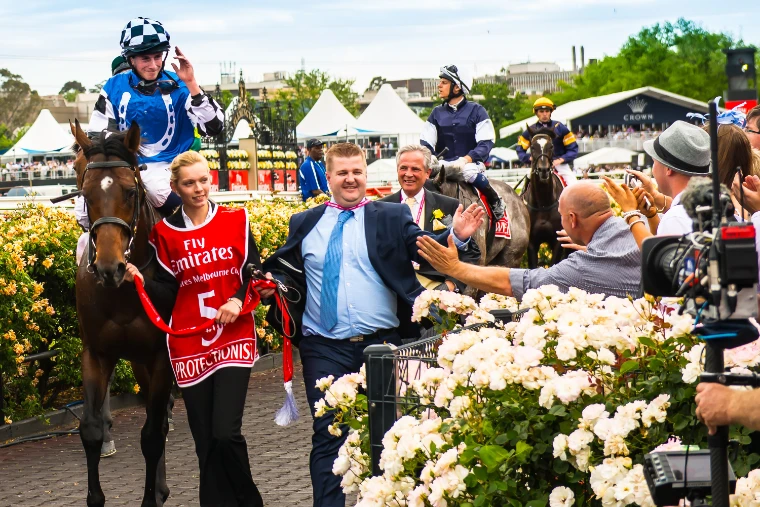 Protectionist, winner of the Melbourne Cup, ridden by Ryan Moore and led in by his strapper past the rails and roses after the race (2014).