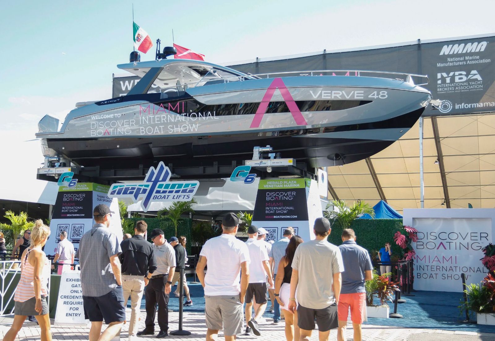 A motor yacht raised on lifts above the entrance gates as visitors arrive at the Miami International Boat Show
