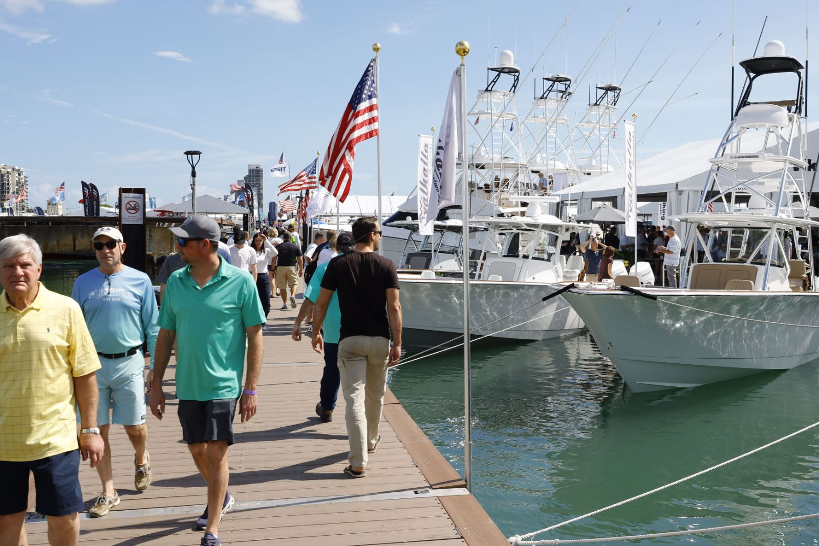 Visitors walking the in-water docks past sportfishing boats and tuna towers at the Miami International Boat Show