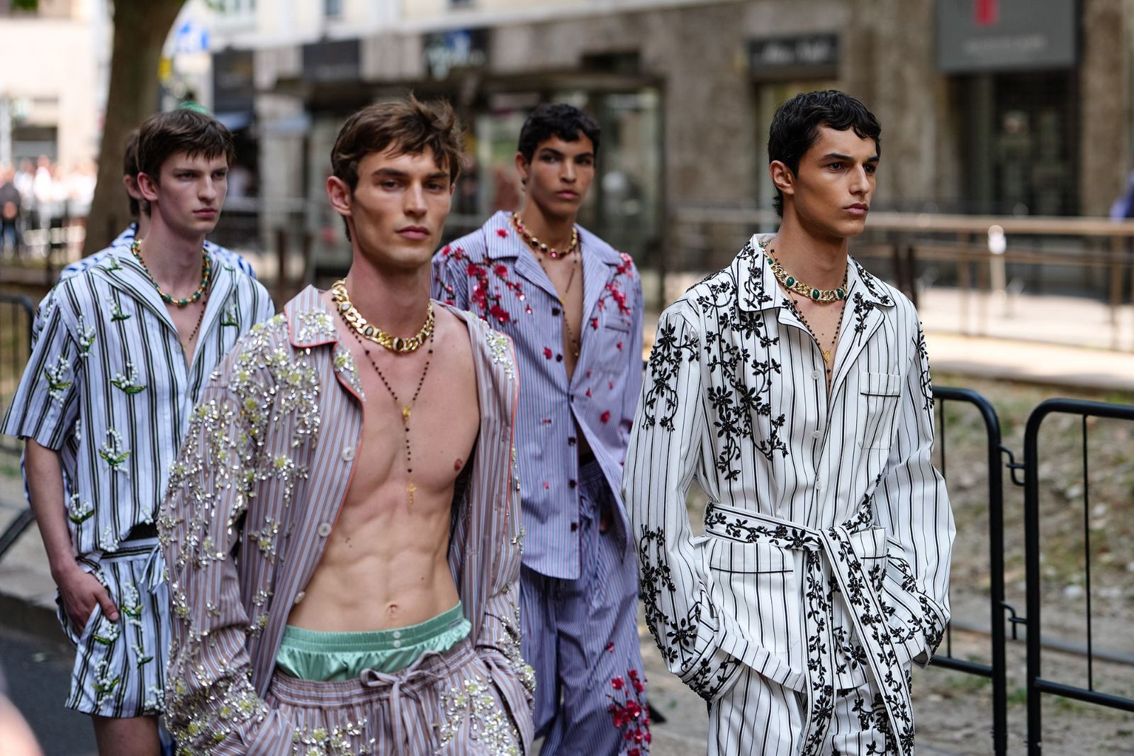 Models in embroidered striped pyjama dressing photographed on the pavement between shows at Milan Fashion Week