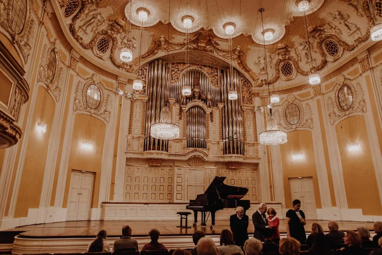 The gilded Großer Saal of the Mozarteum, its organ and chandeliers above an audience after a piano recital. The Großer Saal, Mozarteum, Salzburg, shown for Mozartwoche in the season calendar of The Mansa Court