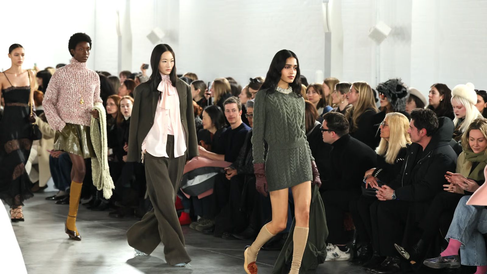 Models walking a daylit runway before a seated front row at New York Fashion Week