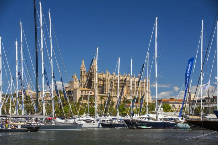 The tall masts of sailing superyachts framing the Gothic front of Palma Cathedral across the harbour, the setting of the Palma International Boat Show, a late-April engagement in the season calendar of The Mansa Court