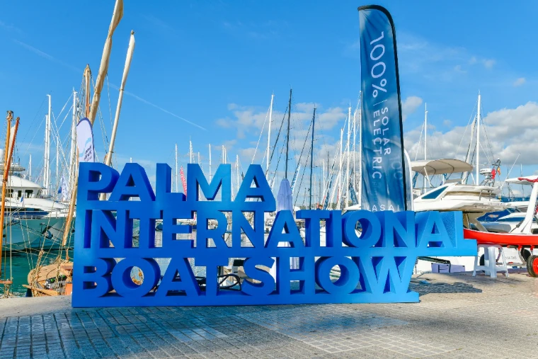 The blue lettered sign of the show on the quay before a forest of masts at the Palma International Boat Show, a late-April engagement in the season calendar of The Mansa Court