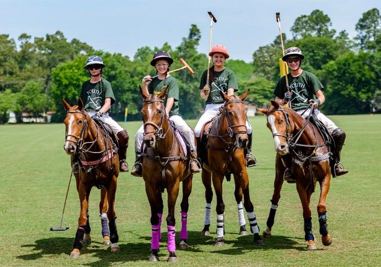 Four riders on polo ponies lined up on a grass field in Bridgehampton, New York, for Polo Lessons and Equestrian Riding, a morning in the season calendar of The Mansa Court