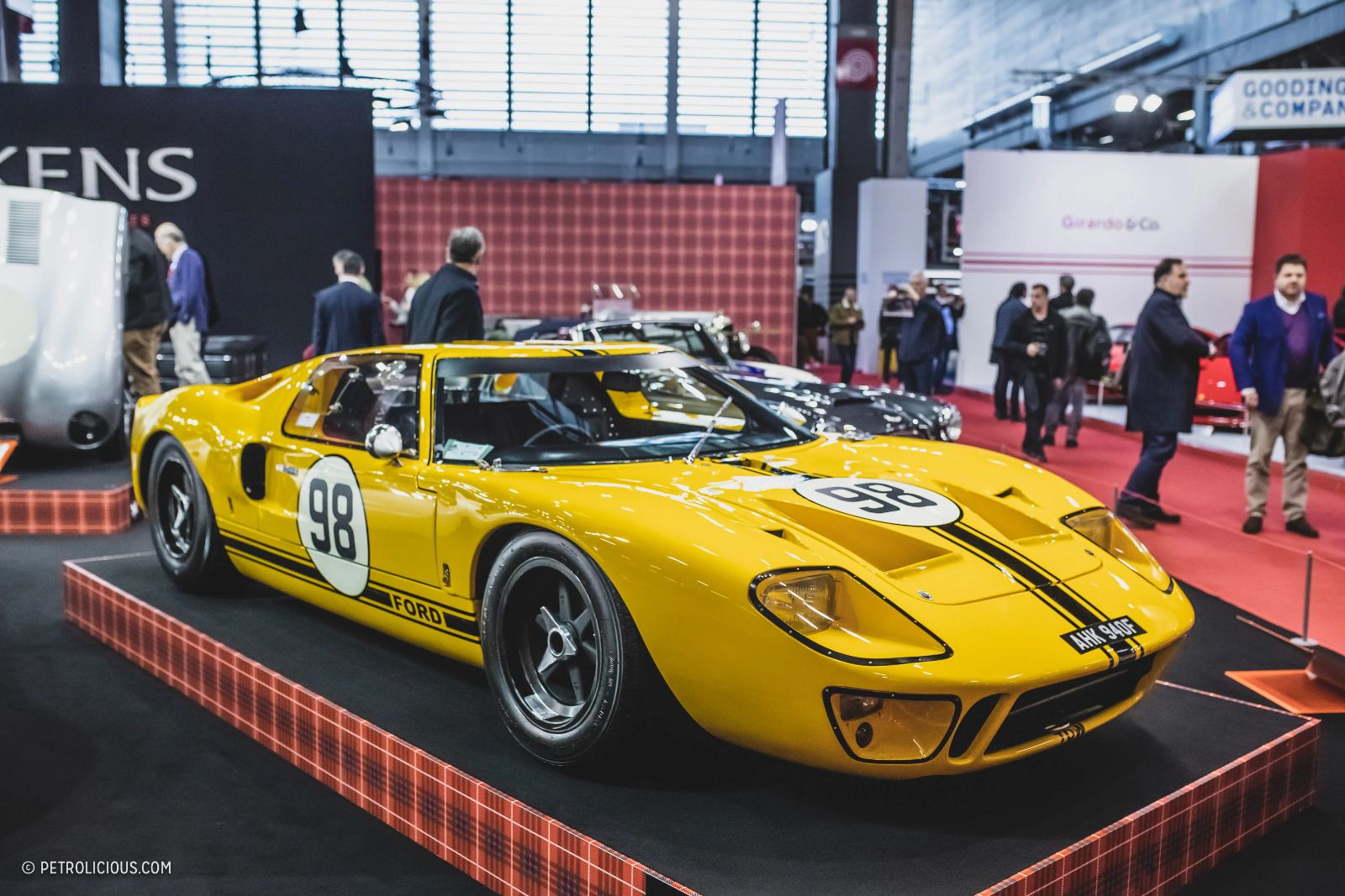 A yellow Ford GT40 in racing livery on a dealer stand at Rétromobile, Paris