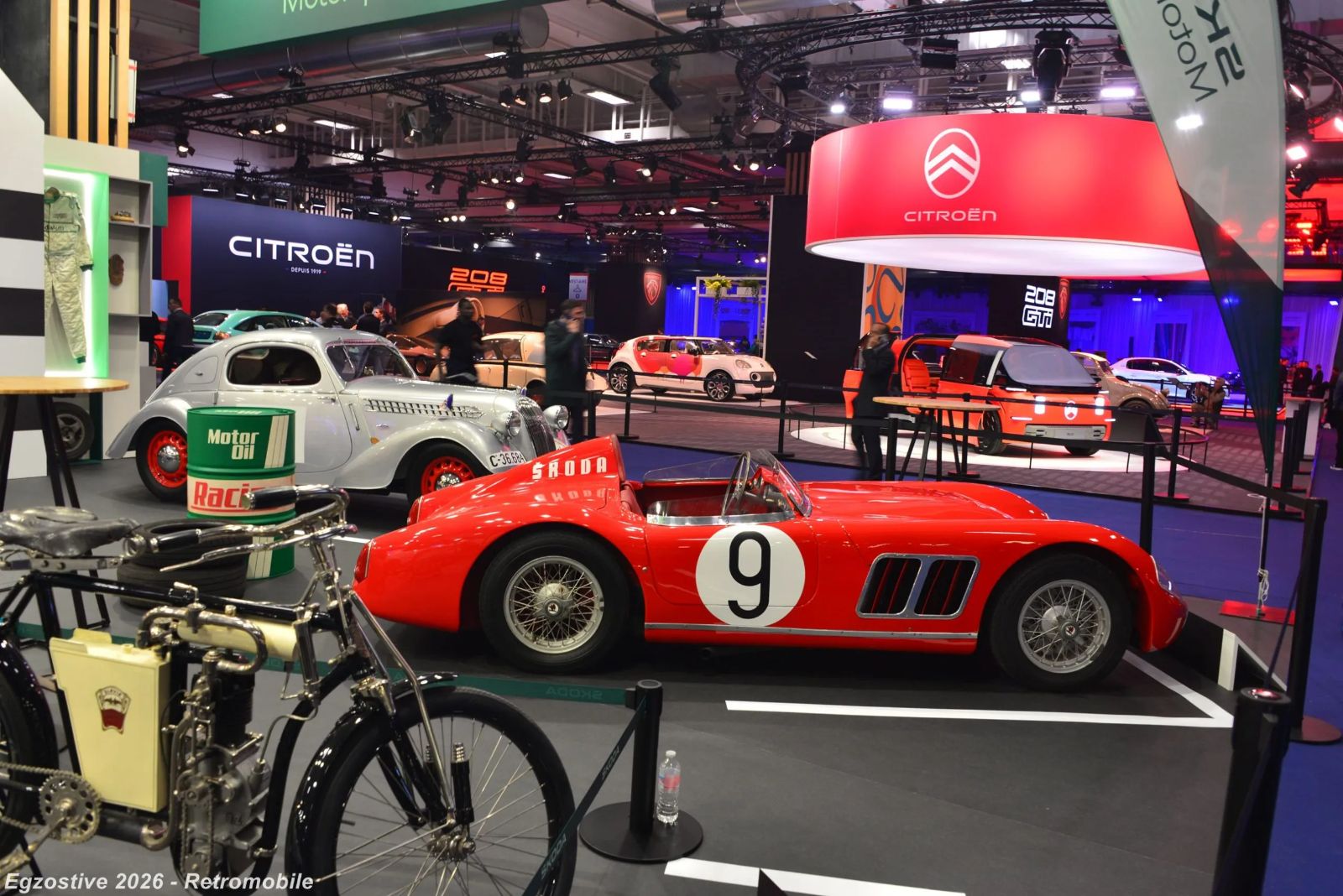 Marque stands and a red competition roadster in the manufacturer halls at Rétromobile, Paris