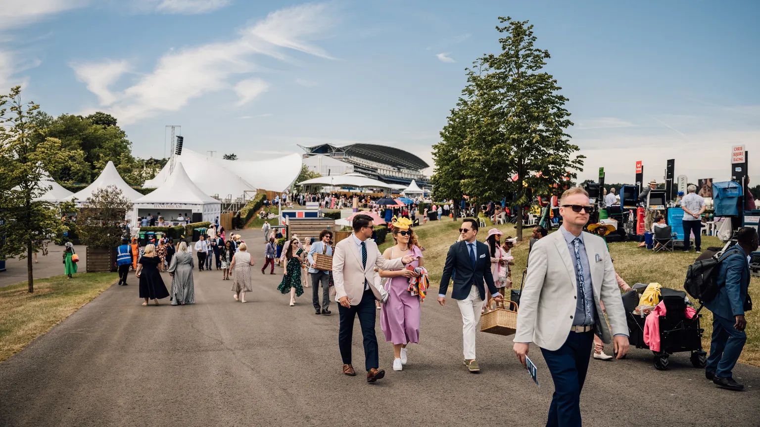 Racegoers in summer dress and hats walking between enclosures at Royal Ascot