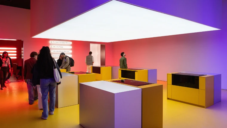 Visitors among yellow and steel kitchen islands under a glowing ceiling panel at the FTK kitchen technology exhibition of the Salone del Mobile.Milano 2024, an April engagement in the season calendar of The Mansa Court