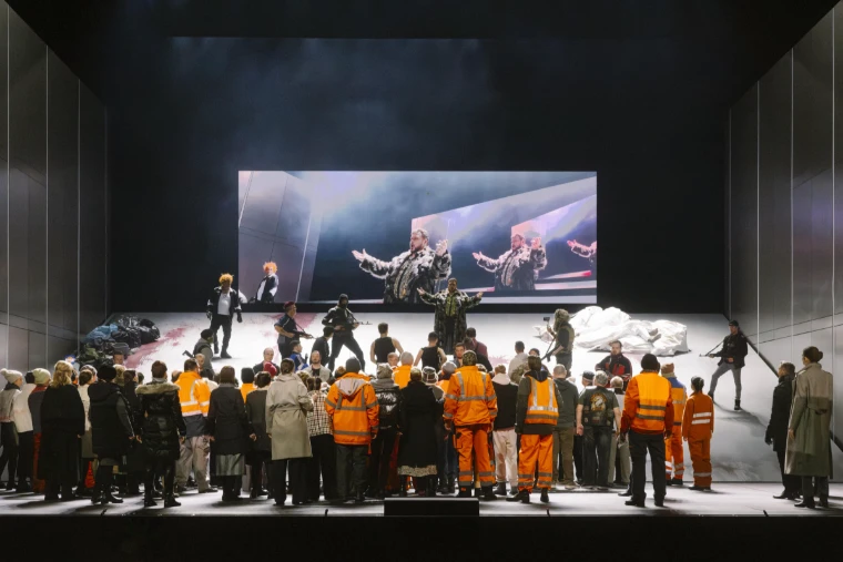 The chorus in orange workwear crowds the stage in a rehearsal of Khovanshchina (2025). Salzburg Easter Festival, Salzburg, in the season calendar of The Mansa Court