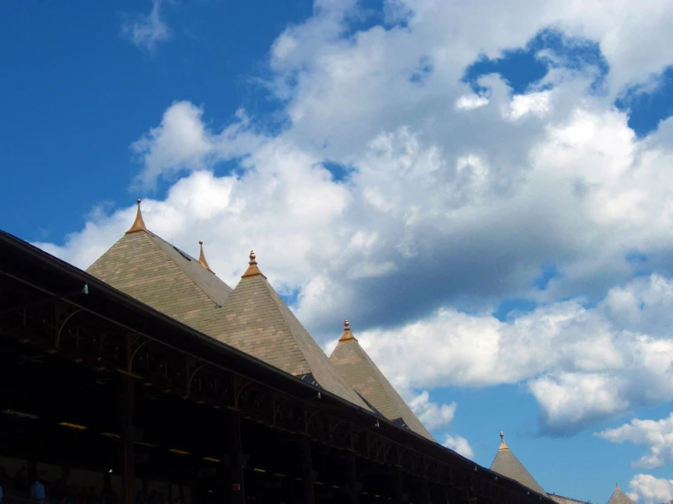 The pointed slate spires of the grandstand roof, topped with copper finials, rise against a deep blue sky full of white clouds (2010).