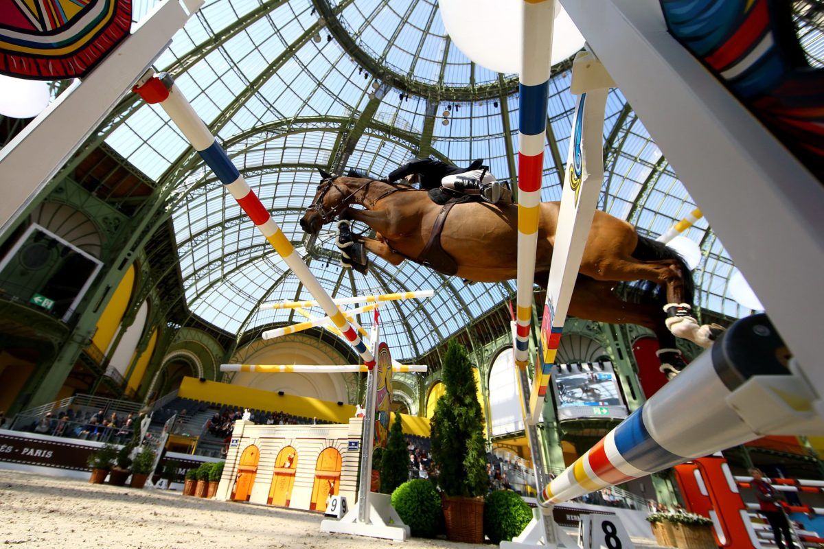 A horse and rider over a fence beneath the glazed roof of the Grand Palais at Saut Hermès, Paris, an engagement in The Mansa Court season