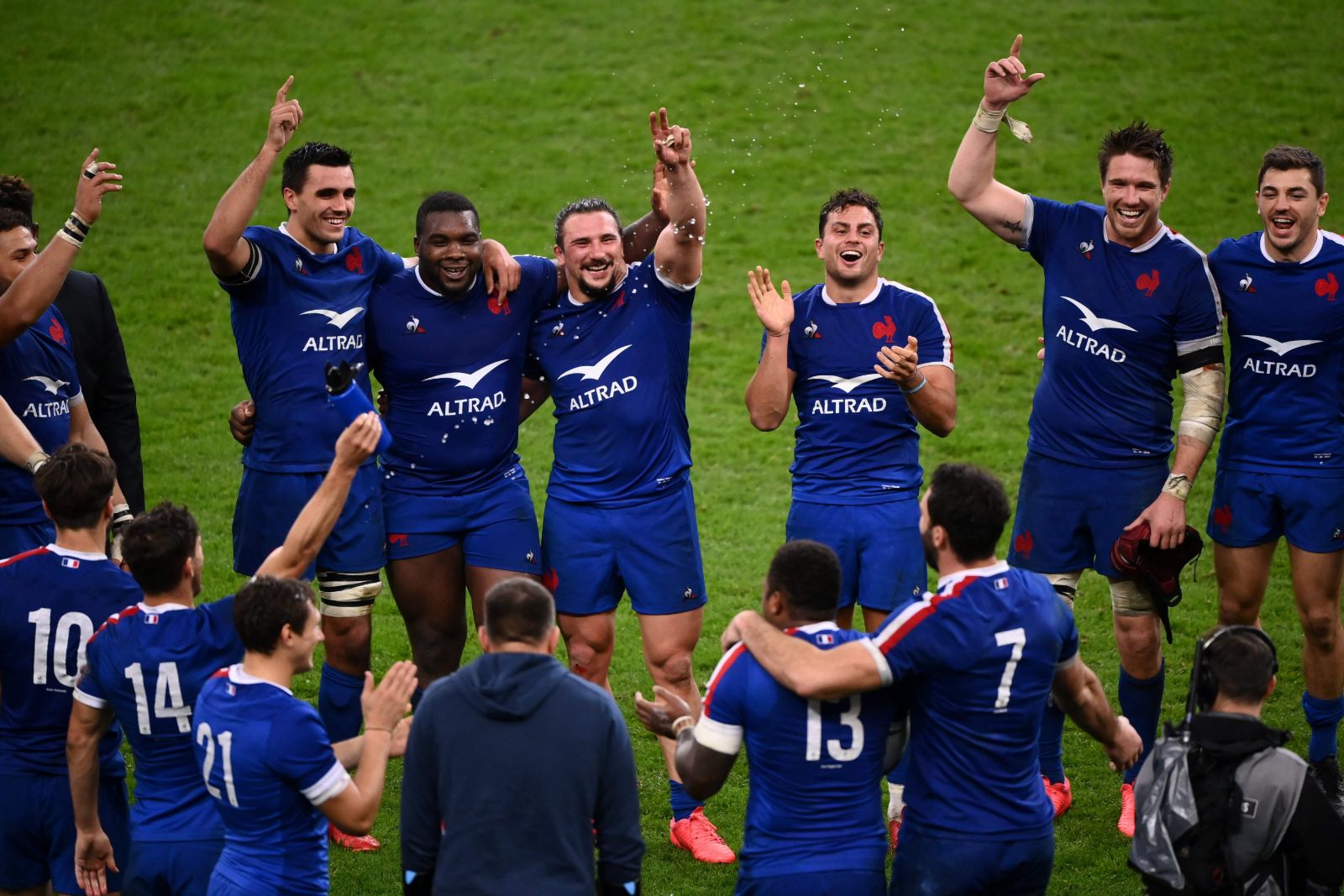 Players in blue arm in arm on the pitch with arms raised to the stands after a Six Nations Championship victory