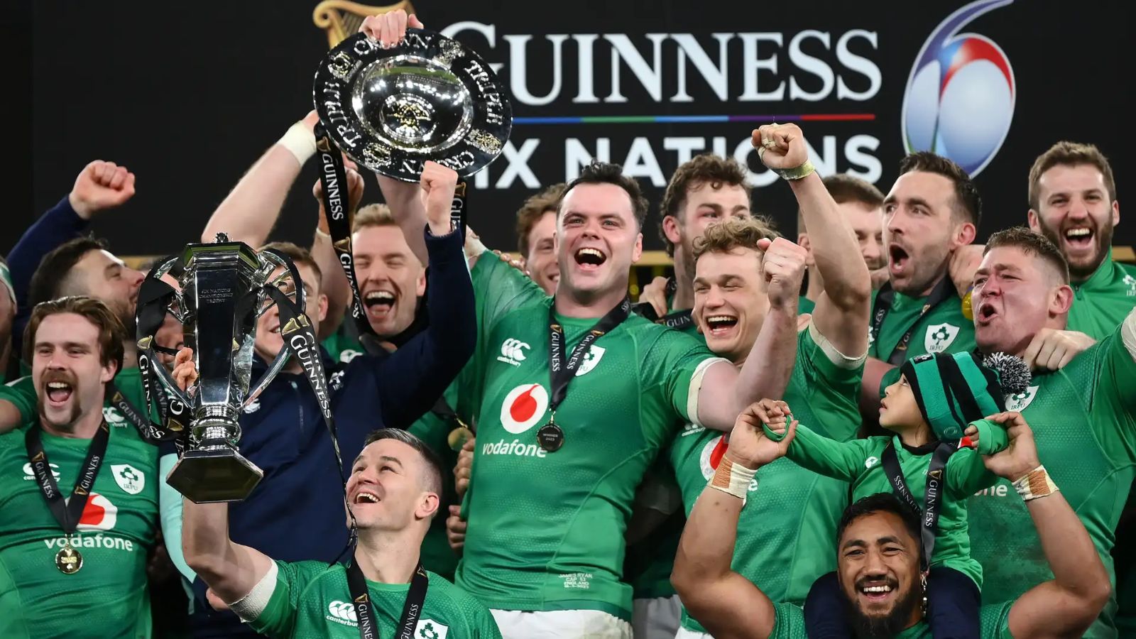 The Ireland squad in green raising the Championship trophy and the Triple Crown salver before the Guinness Six Nations backdrop