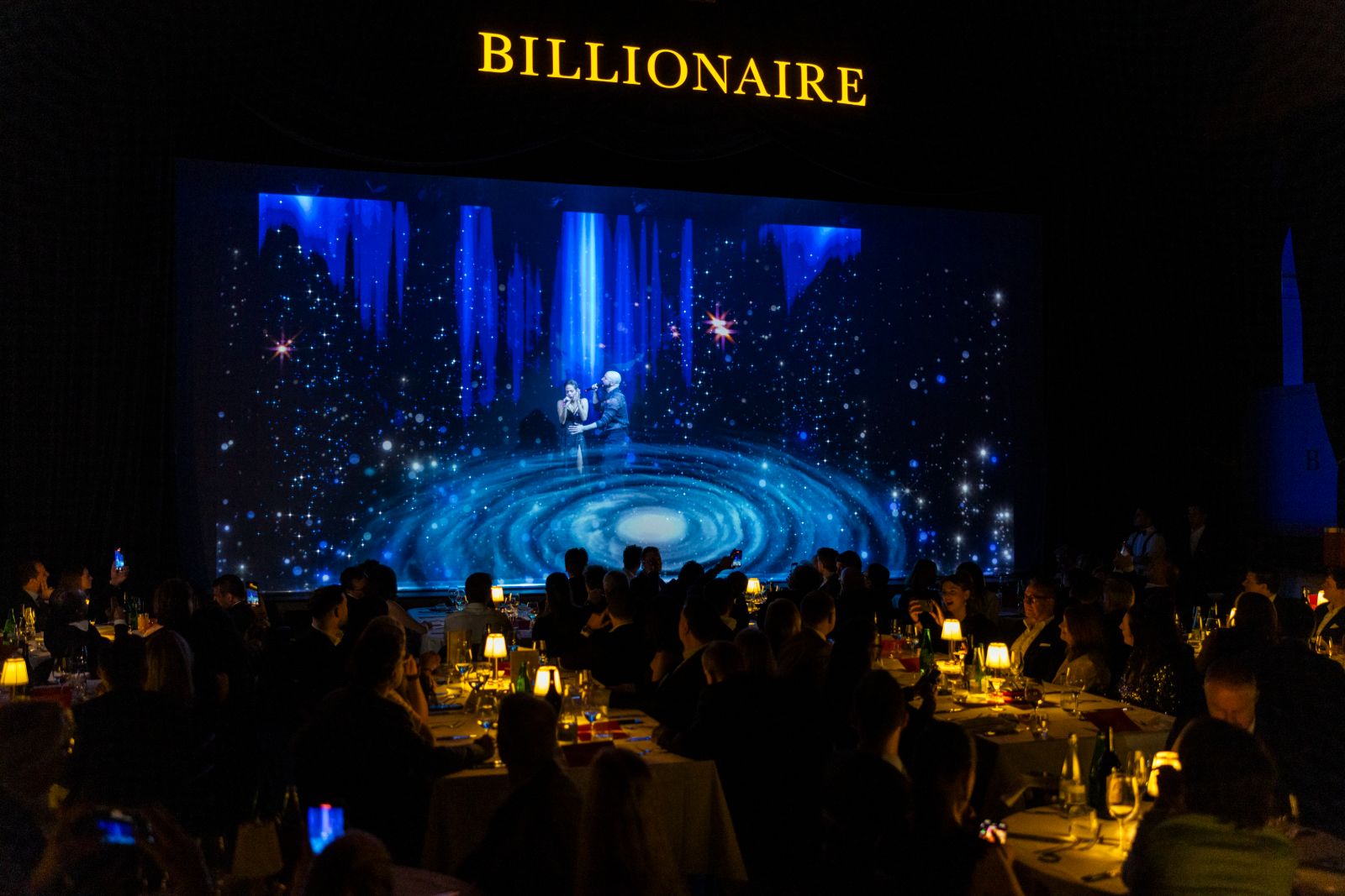 Singers performing before a candlelit room of dining tables at the Grand Gourmet closing show of the St. Moritz Gourmet Festival
