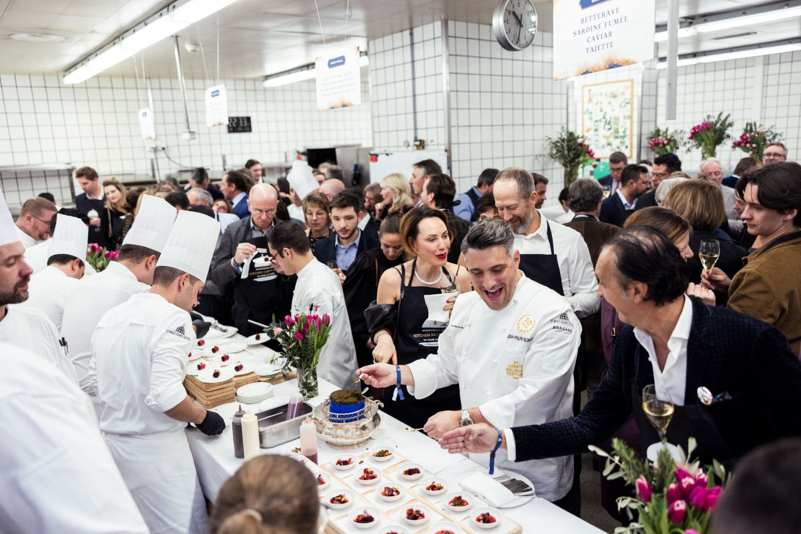 Guest chefs plating beetroot, smoked sardine and caviar for guests crowded into a hotel kitchen at the Kitchen Party of the St. Moritz Gourmet Festival