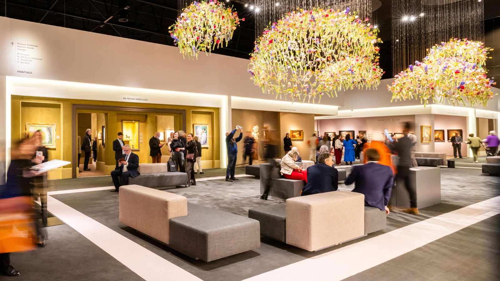 The paintings section of TEFAF Maastricht under suspended flower chandeliers, where The Mansa Court seeks passage for members each March