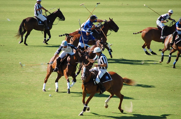 Players of La Dolfina and Pilará Piaget converge on the ball at a gallop, with an umpire alongside (2012).