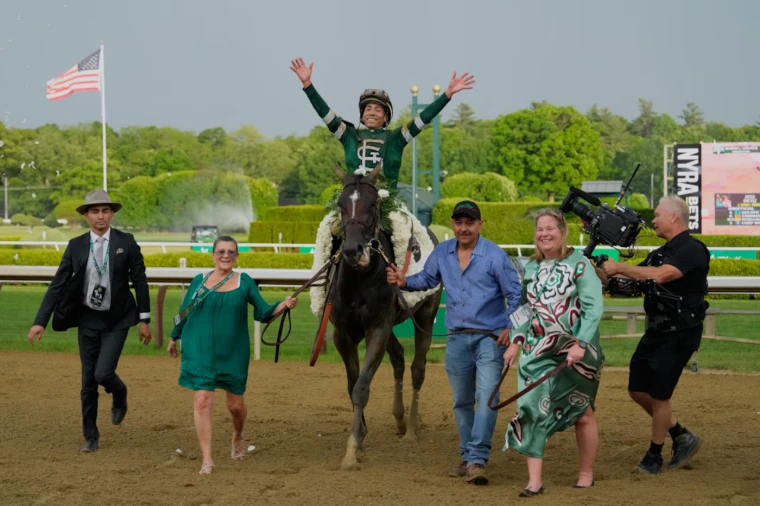 The winner is led in under his blanket of white carnations, the jockey’s arms raised. The Belmont Stakes, the final leg of the Triple Crown, in the season calendar of The Mansa Court