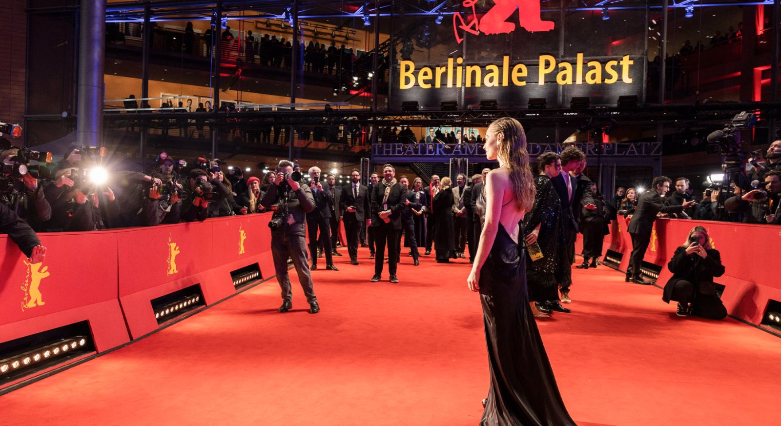 An actress in a black gown turning for the photographers on the red carpet beneath the Berlinale Palast sign at The Berlinale