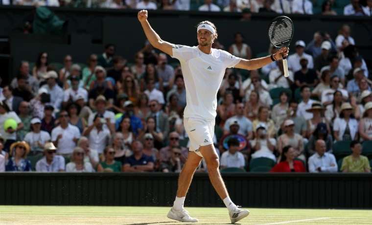 A player in tennis whites raising his arms in victory on the grass before a sunlit crowd at The Championships, Wimbledon, London, an engagement in the season calendar of The Mansa Court